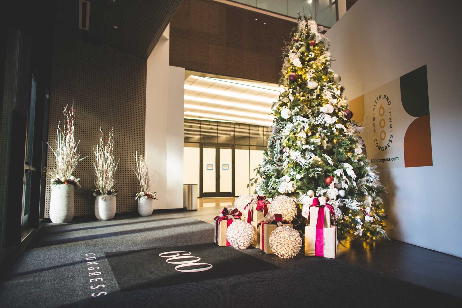 White and gold tree in an office space with gift box decor and lighted spheres