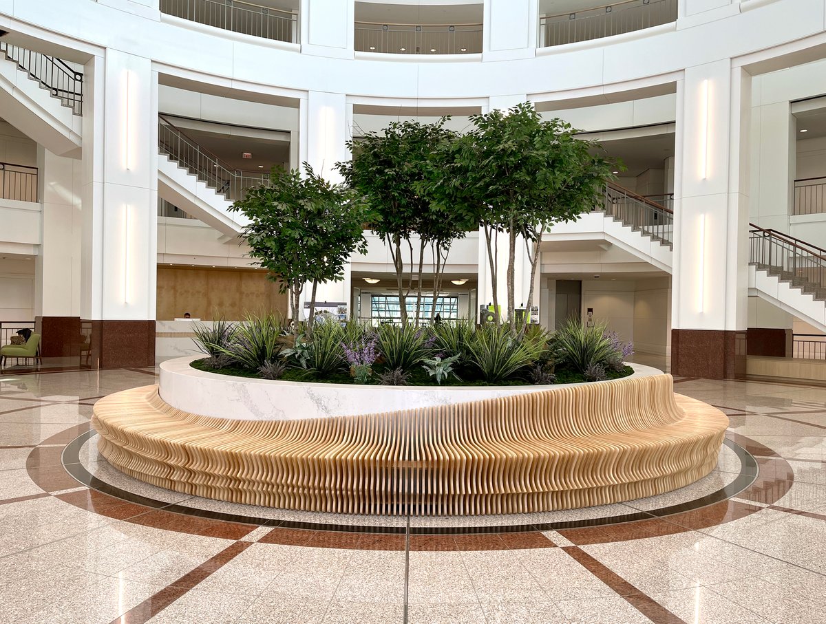 Large faux plant arrangement featuring synthetic trees, plants, and flowers in the lobby of a building in Dallas, Texas