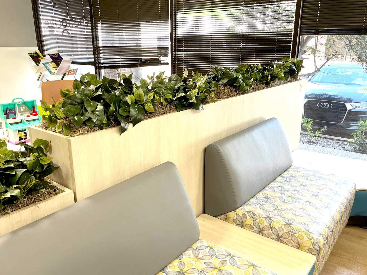 A clinic waiting area with plants between the sections 