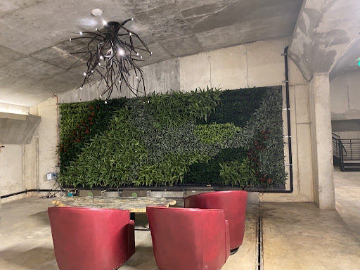 a living wall by a paise area with three red chairs 