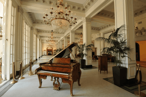 A piano i a hotel with indoor plants at every pillar 