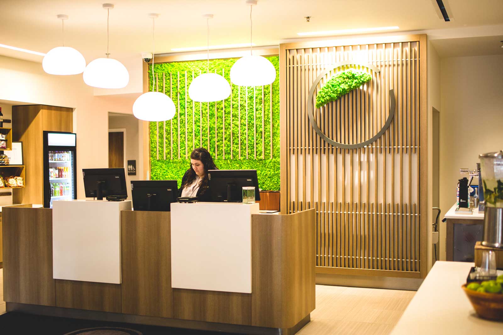 Image of a receptionist at a hotel reception with green living walls behind the desk 